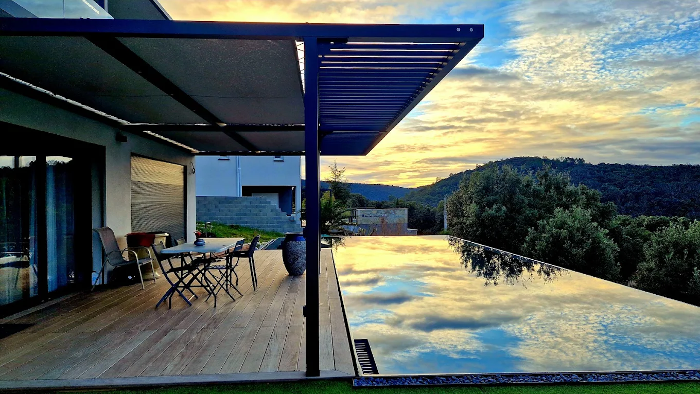 Piscine à débordement avec terrasse bois construite par Pro'Renov, coucher de soleil dans le Gard